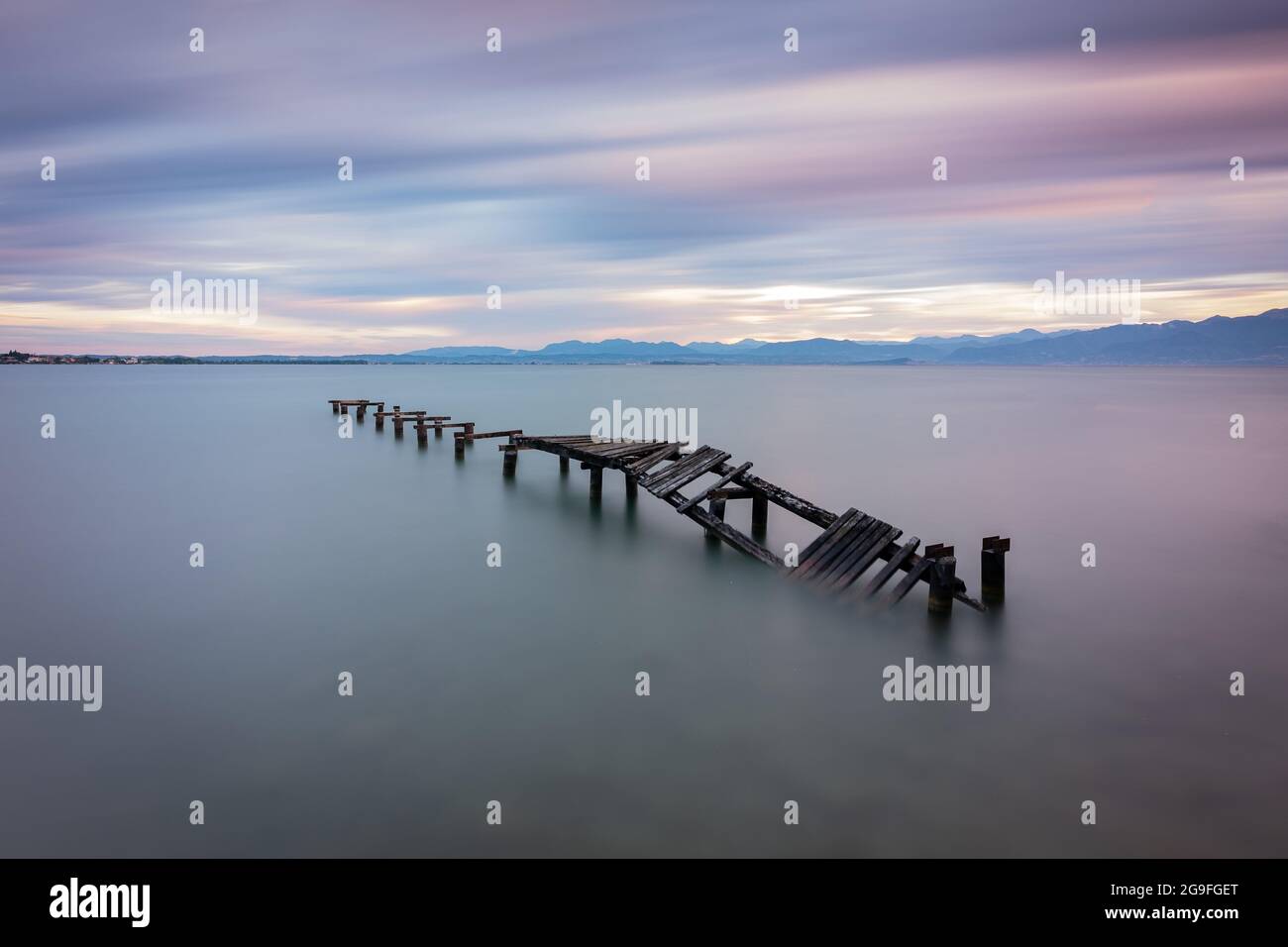 Abandoned wooden pier in lake during sunrise, long exposure Stock Photo