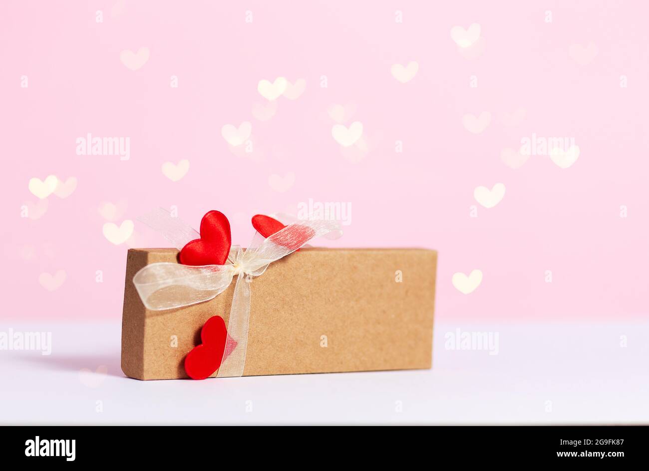 present box with hearts composition for Valentine's, Mother's or Women's Day. Heart bokeh on pink wooden background. Still-life. Copy space Stock Photo