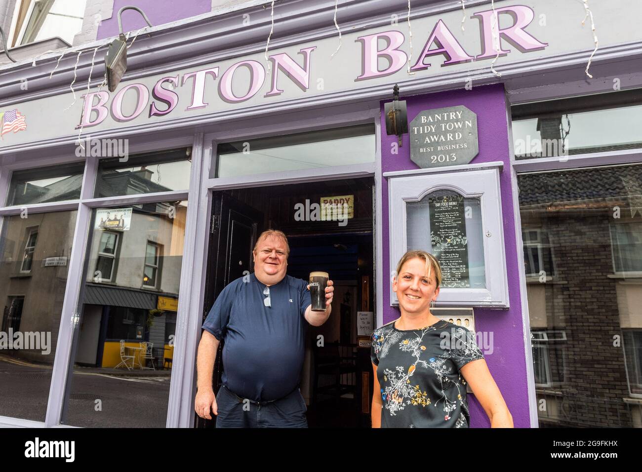 Bantry, West Cork, Ireland. 26th July, 2021. Today the so called 'wet pubs' reopened for the first time since the start of the pandemic. Pictured is Boston Bar owner, Danny Collins, brother of independent TD Michael Collins, who reopened his pub at 10.30 this morning and bar staff Helen Martin. Credit: AG News/Alamy Live News Stock Photo