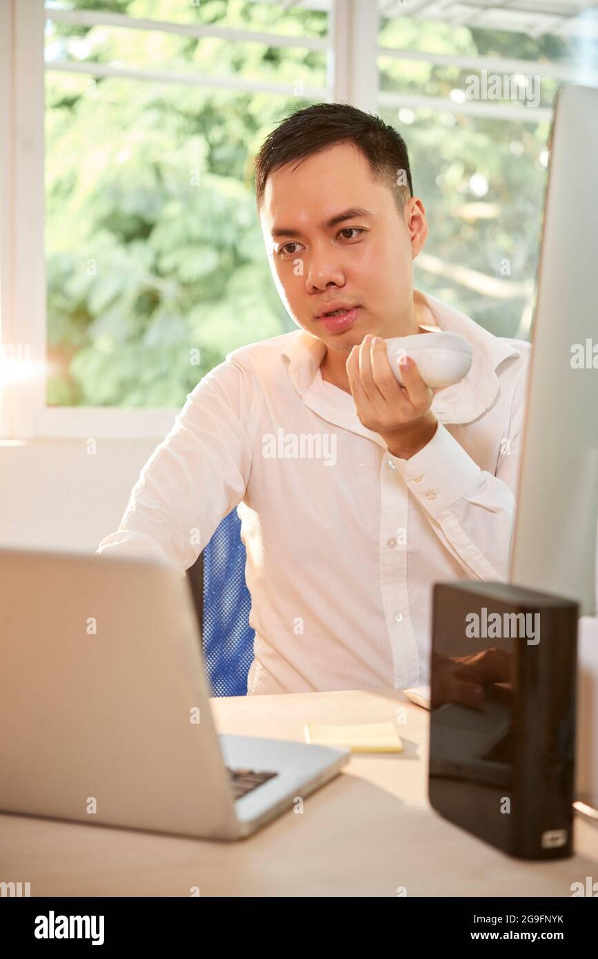 Serious young entrepreneur working at office desk and recording voice