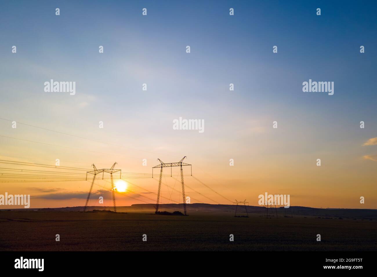 Dark silhouette of high voltage towers with electric power lines at ...