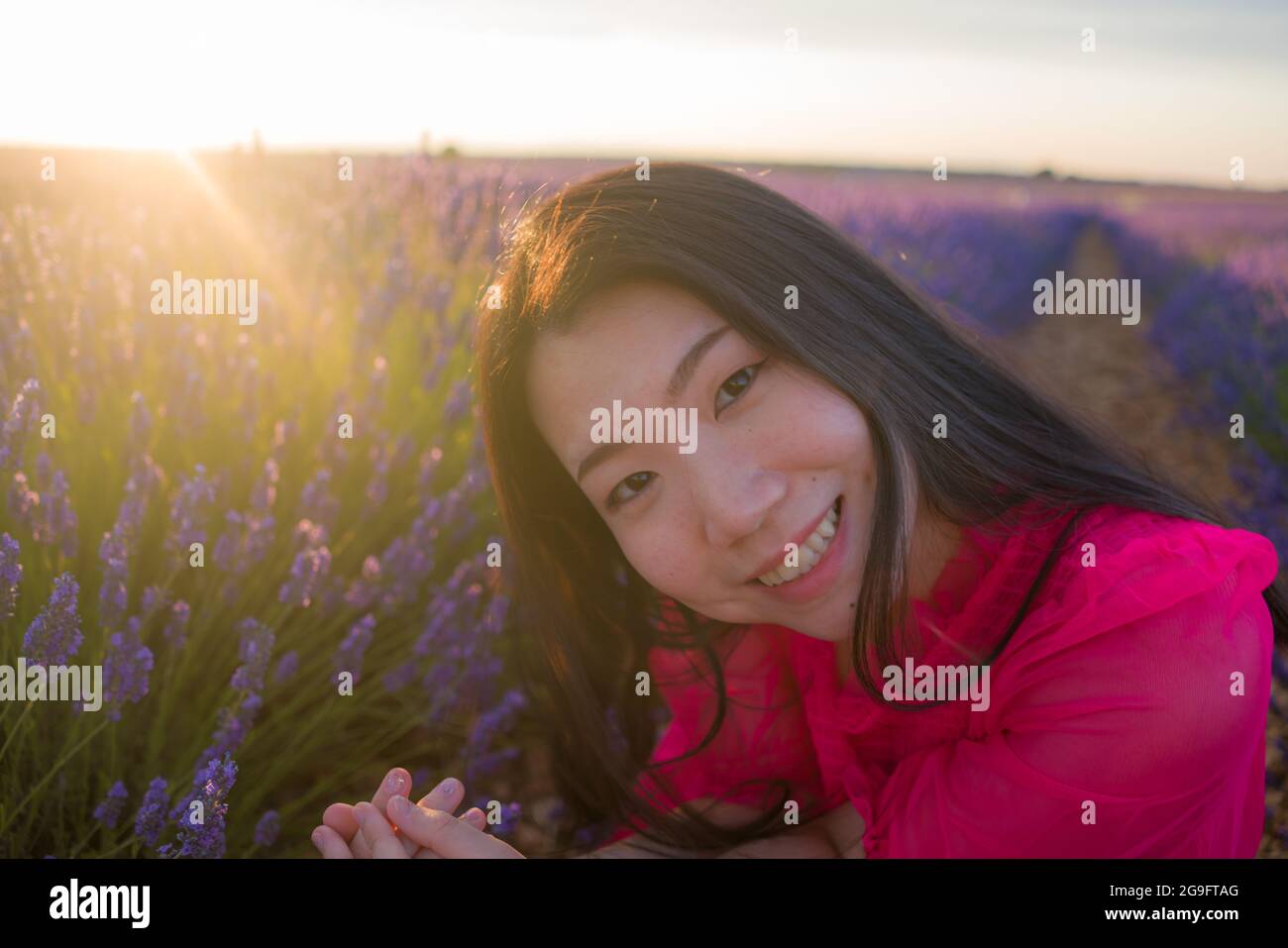 young happy and beautiful Asian Chinese woman in Summer dress enjoying free and playful in romantic and lovely purple lavender flowers field in nature Stock Photo