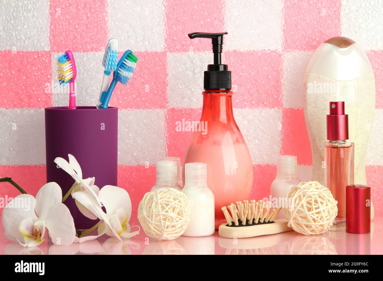 Bath accessories on shelf in bathroom on pink tile wall background ...