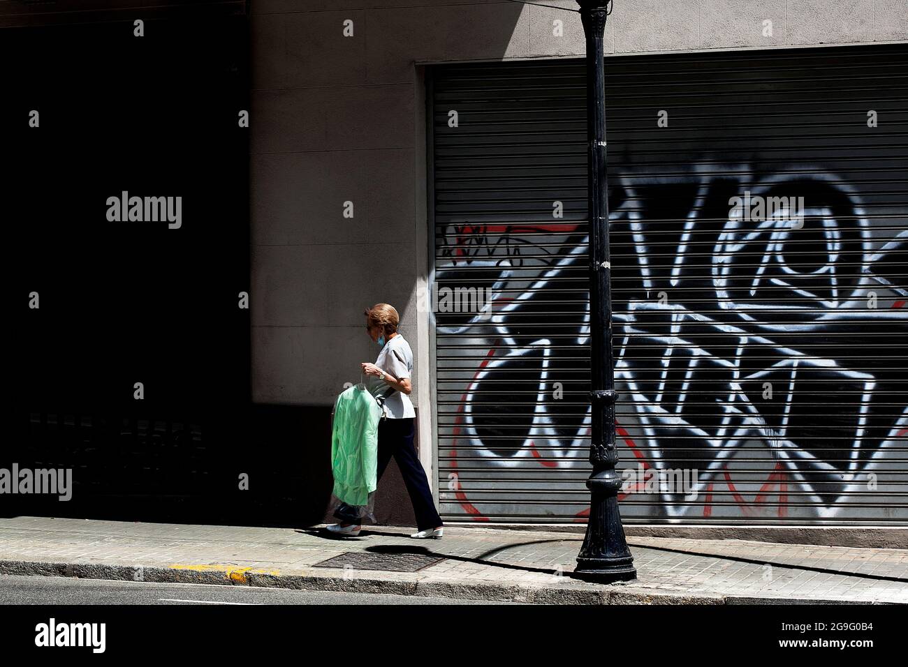 Woman carrying her dry cleaning, Barcelona, Spain. Stock Photo