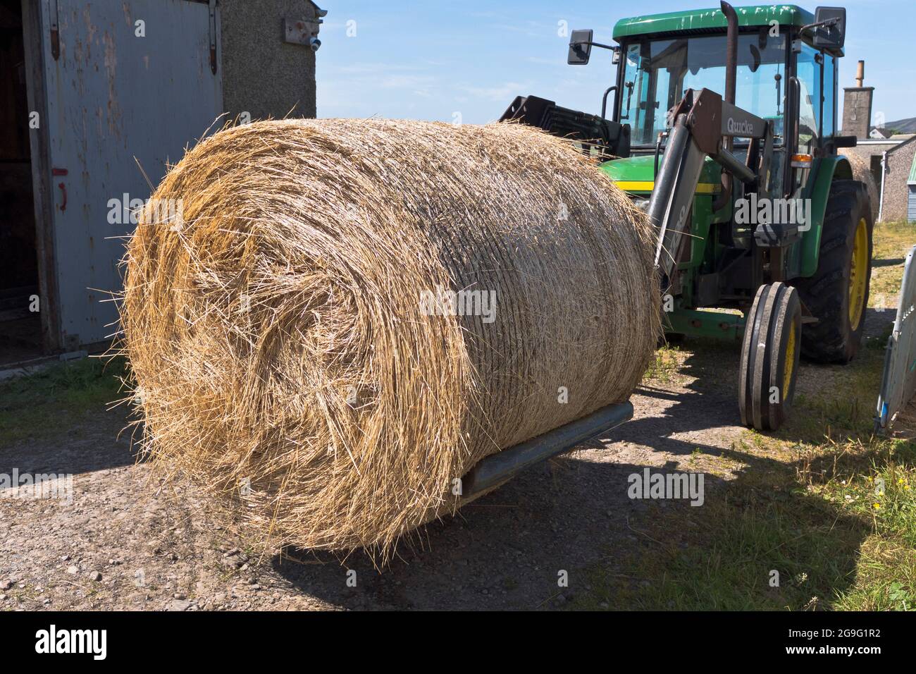 dh Bales FARMING UK Round straw bale on tractor lifter front loader forklift hay farm machinery fork attachment Stock Photo