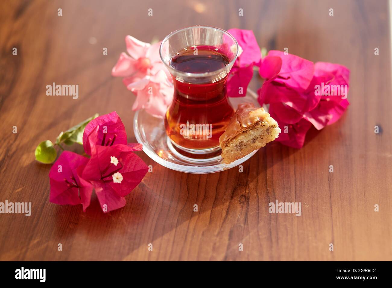 Turkish delight and traditional glass of turkish tea with bougainvillea flowers. Romantic dinner concept. Relaxing, calming drink Travel Turkey concept. Bright relaxing drink. High quality photo Stock Photo
