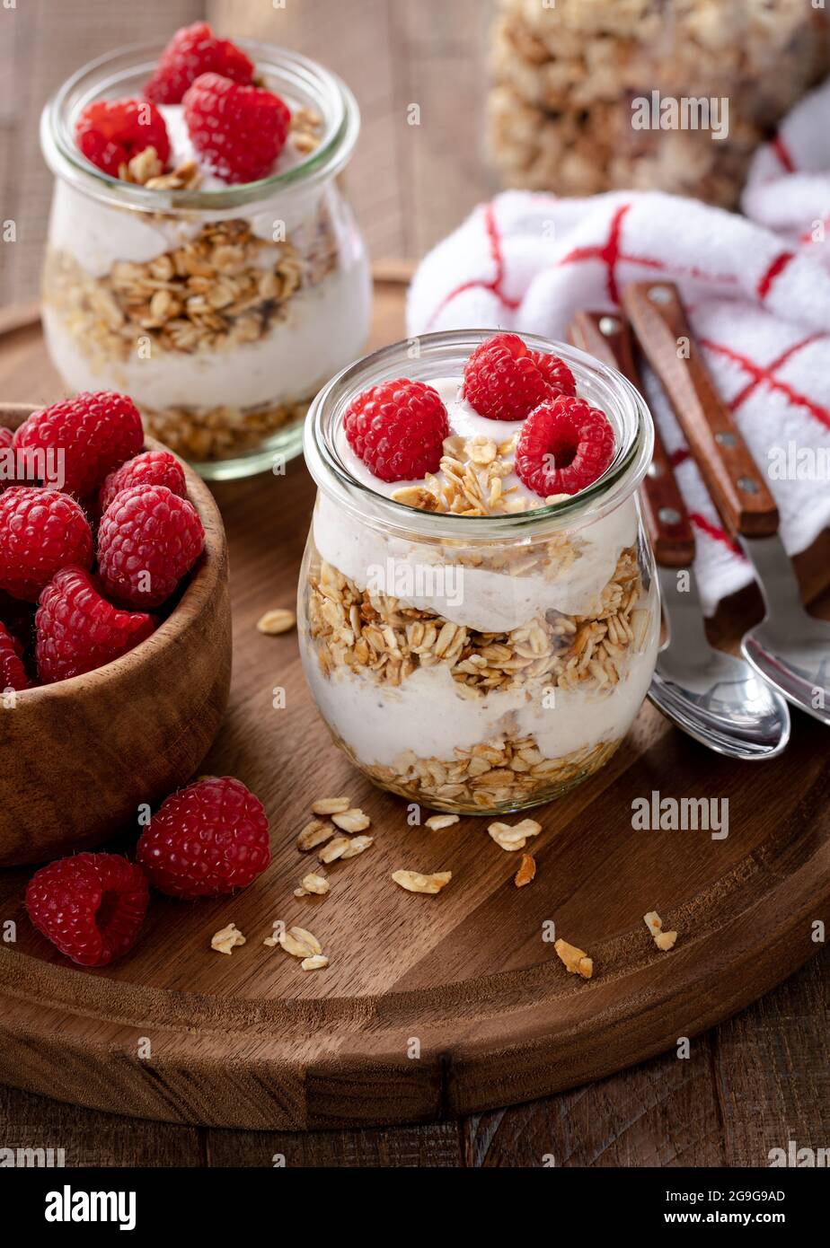 Granola parfait with yogurt and fresh raspberries on a wooden platter Stock Photo