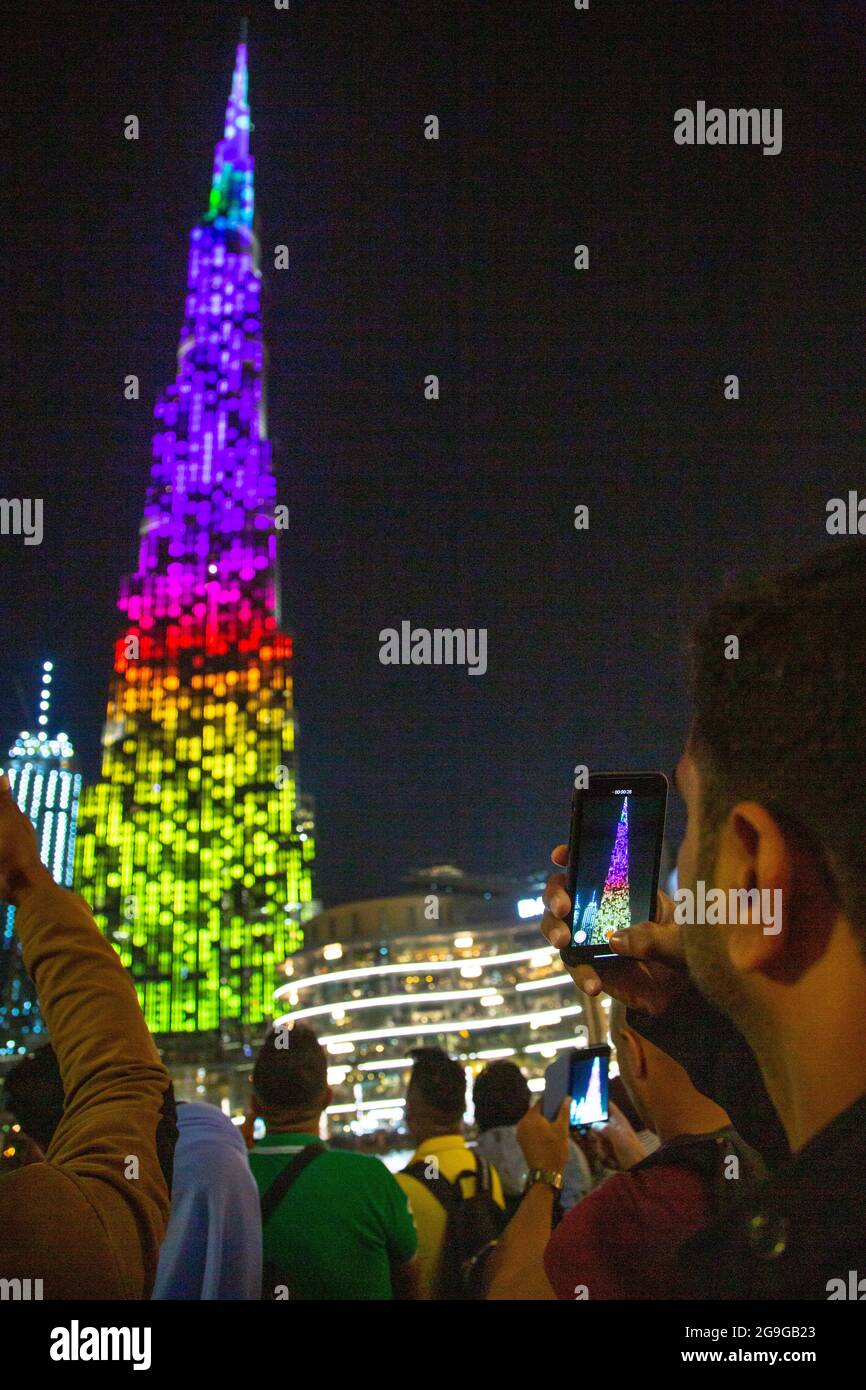 A man records the light show on Burj Khalife, Dubai, UAE. --- Burj Khalifa, the tallest building in the world is the backdrop for spectacularly light Stock Photo