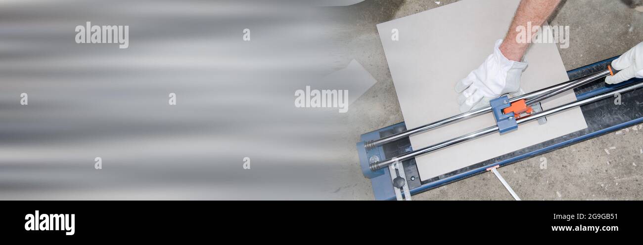 Tiler using a tile cutter on grey background Stock Photo