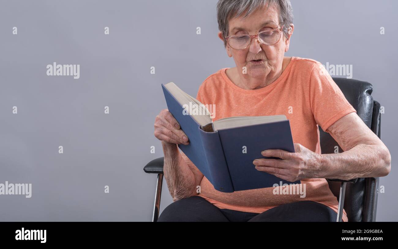 Old woman sitting reading a book Stock Photo - Alamy