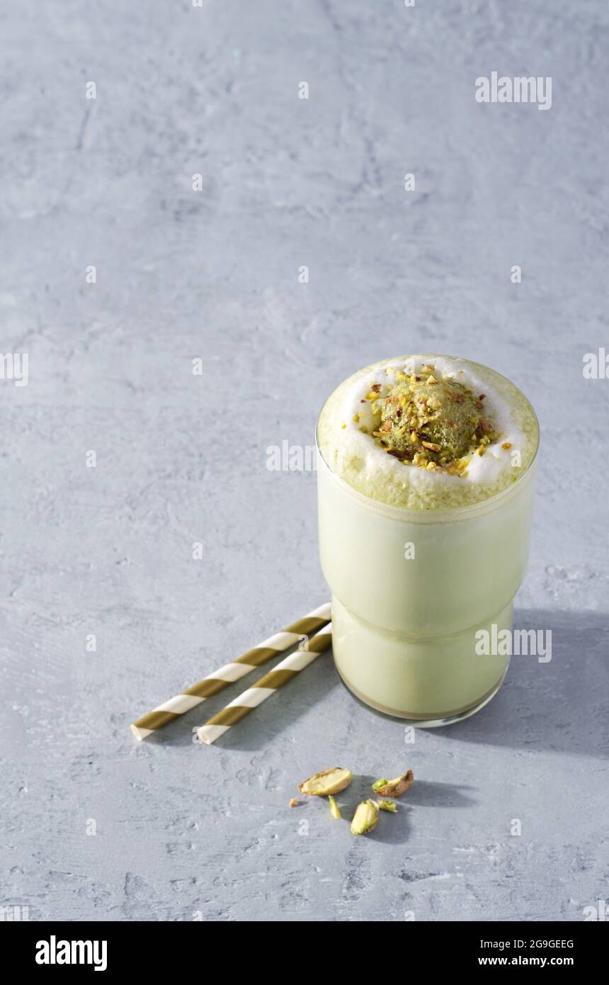 Green coffee matcha latte with foam sprinkled with nuts on a concrete background with copying space Stock Photo