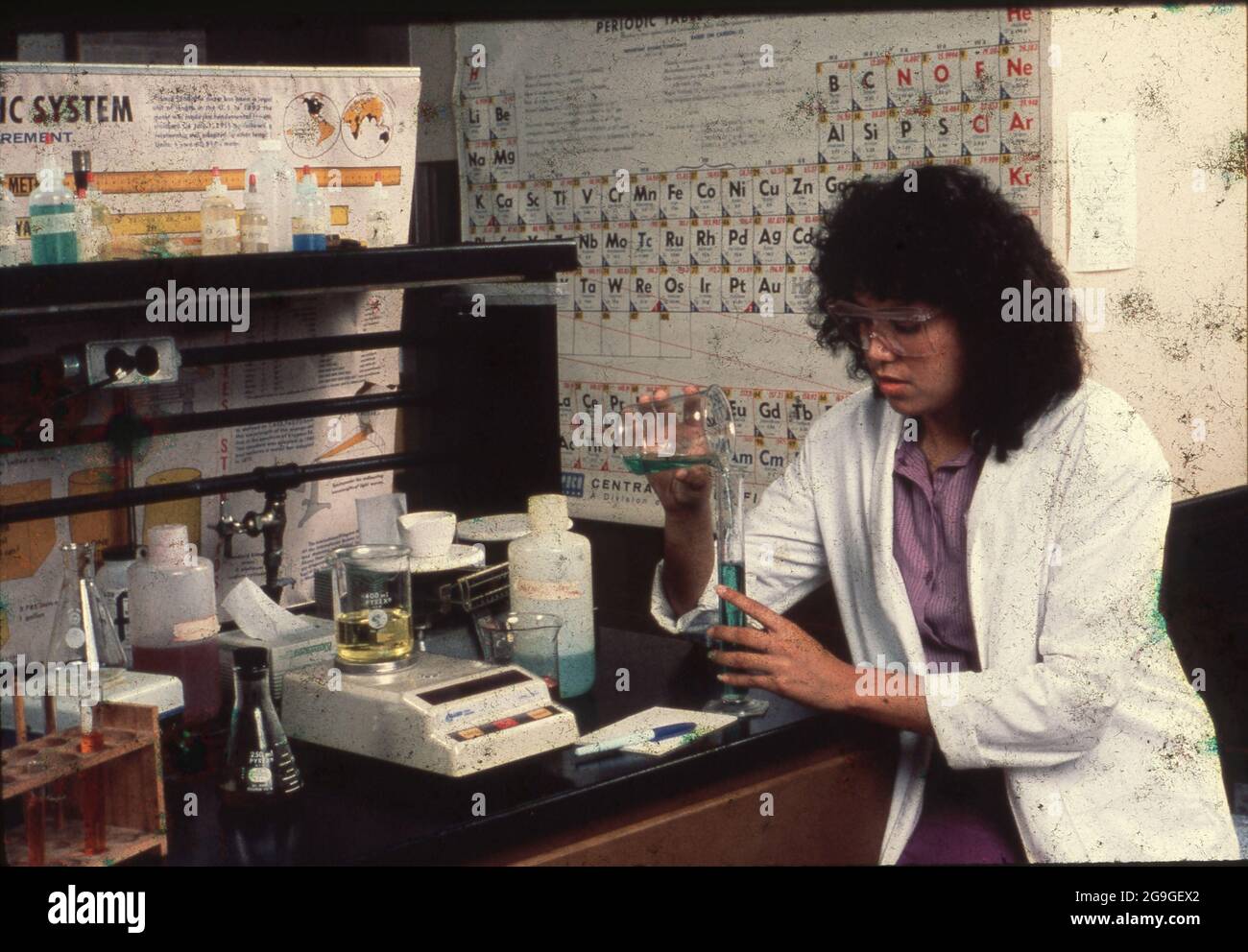 Austin, Texas USA, 1990: Hispanic college student measures a liquid as she pours it from a beaker into a graduated cylinder in a chemistry lab. ©Bob Daemmrich Stock Photo
