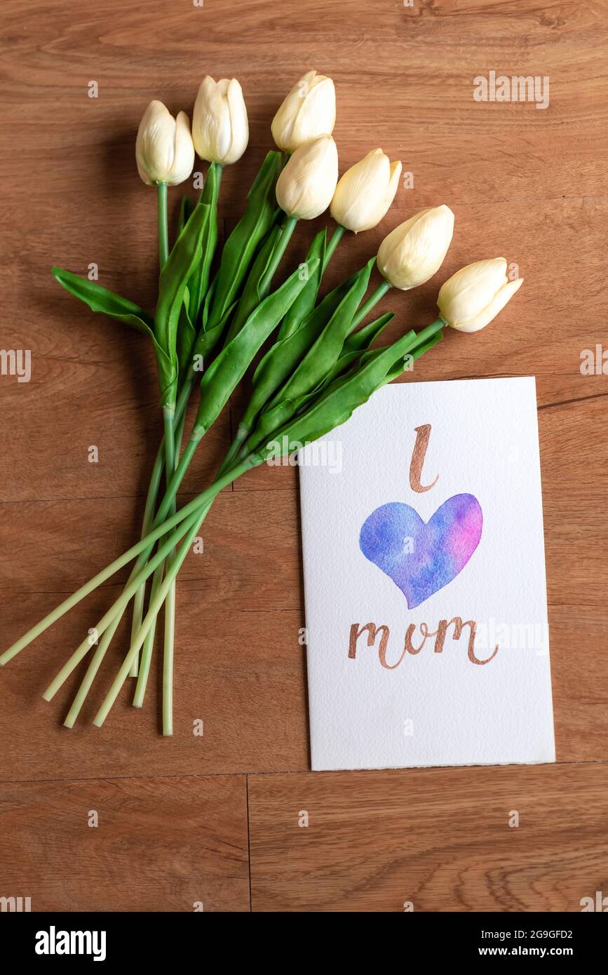 Watercolour card with i love mom word and flower on wooden floor Stock Photo