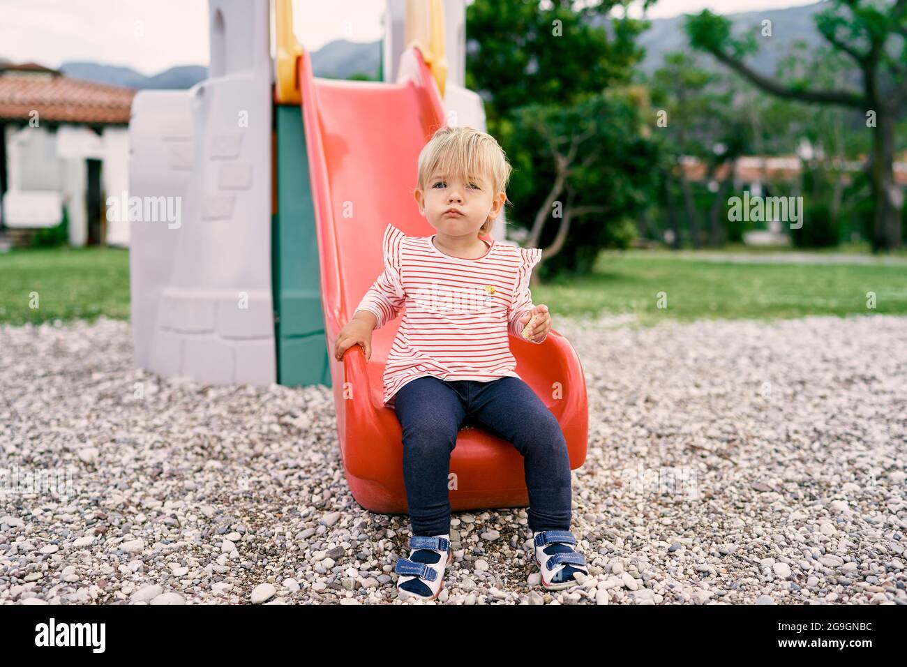 Little girl sitting on a slide in the playground Stock Photo - Alamy
