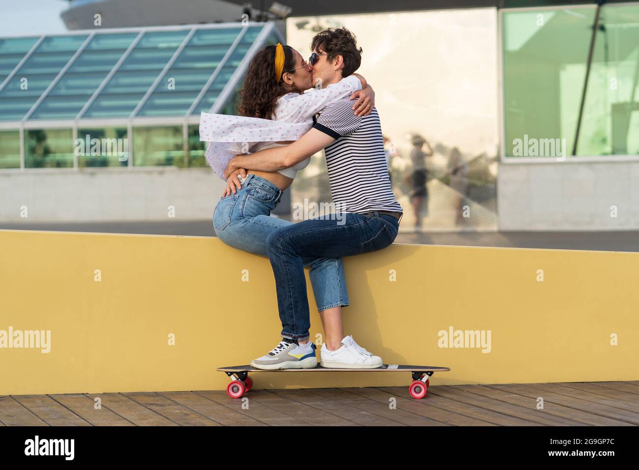 Stylish couple kissing sitting in skatepark. Young cute ...