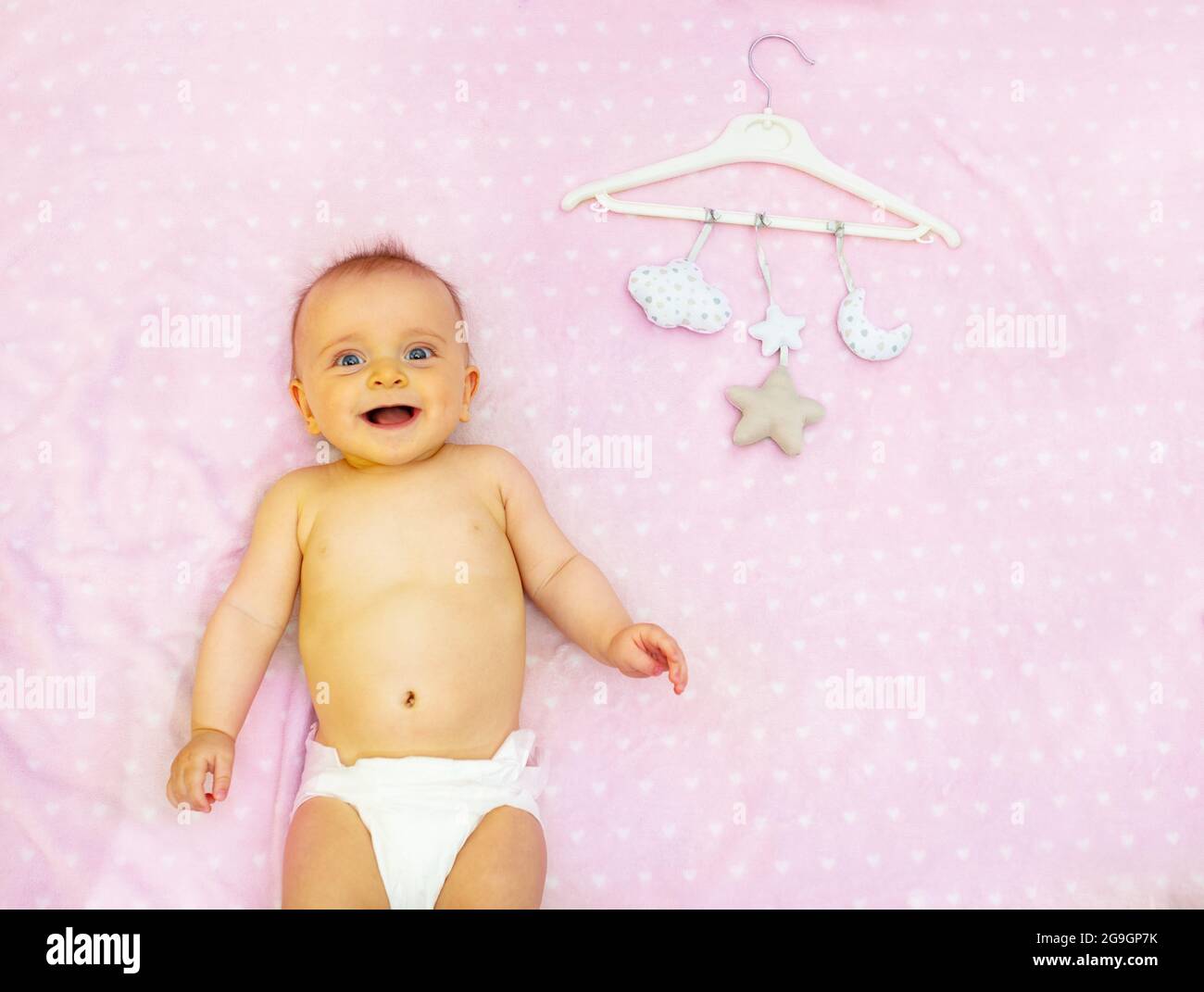 Little laughing baby girl, mobile toys on hanger Stock Photo Alamy