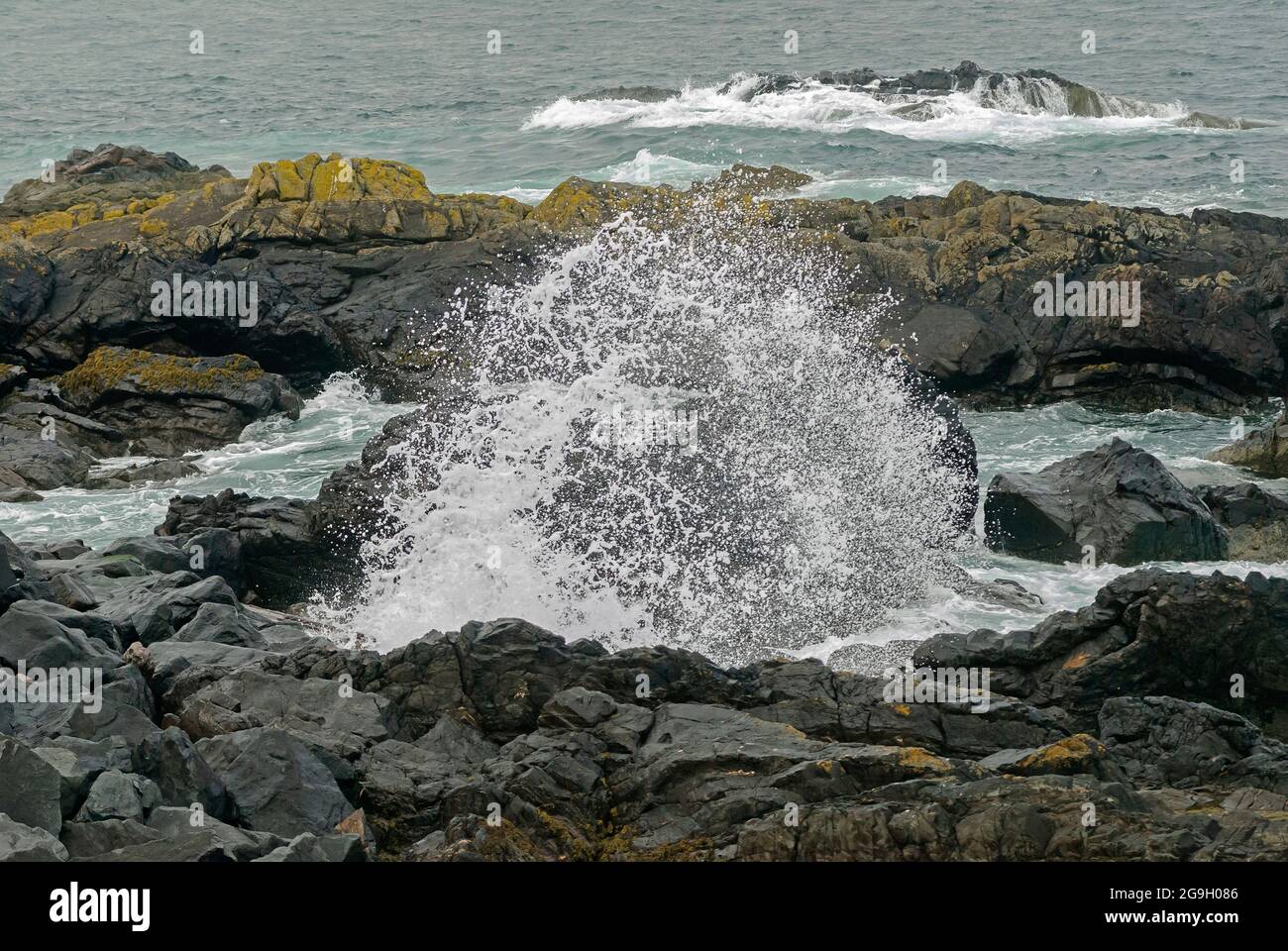 Waves and spray crashing against rocks Stock Photo