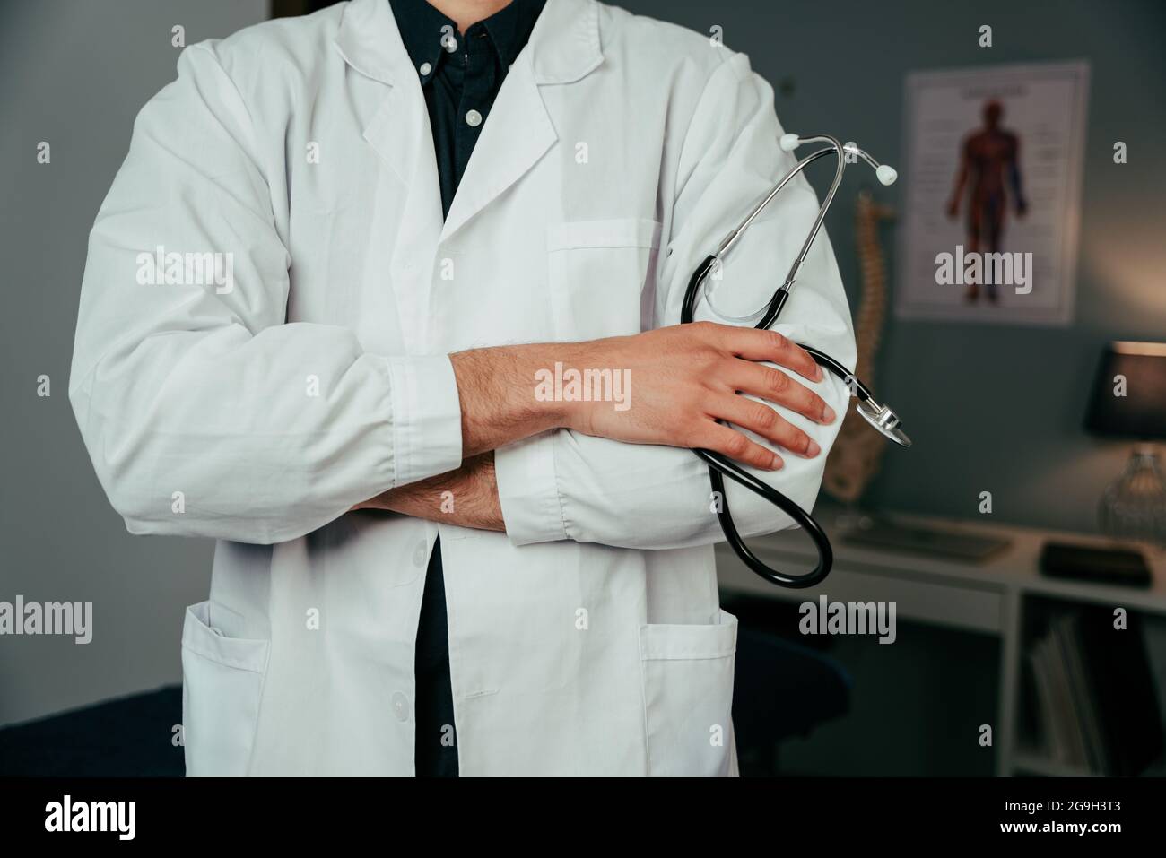 Close up mixed race male doctor standing in office with arms crossed Stock Photo