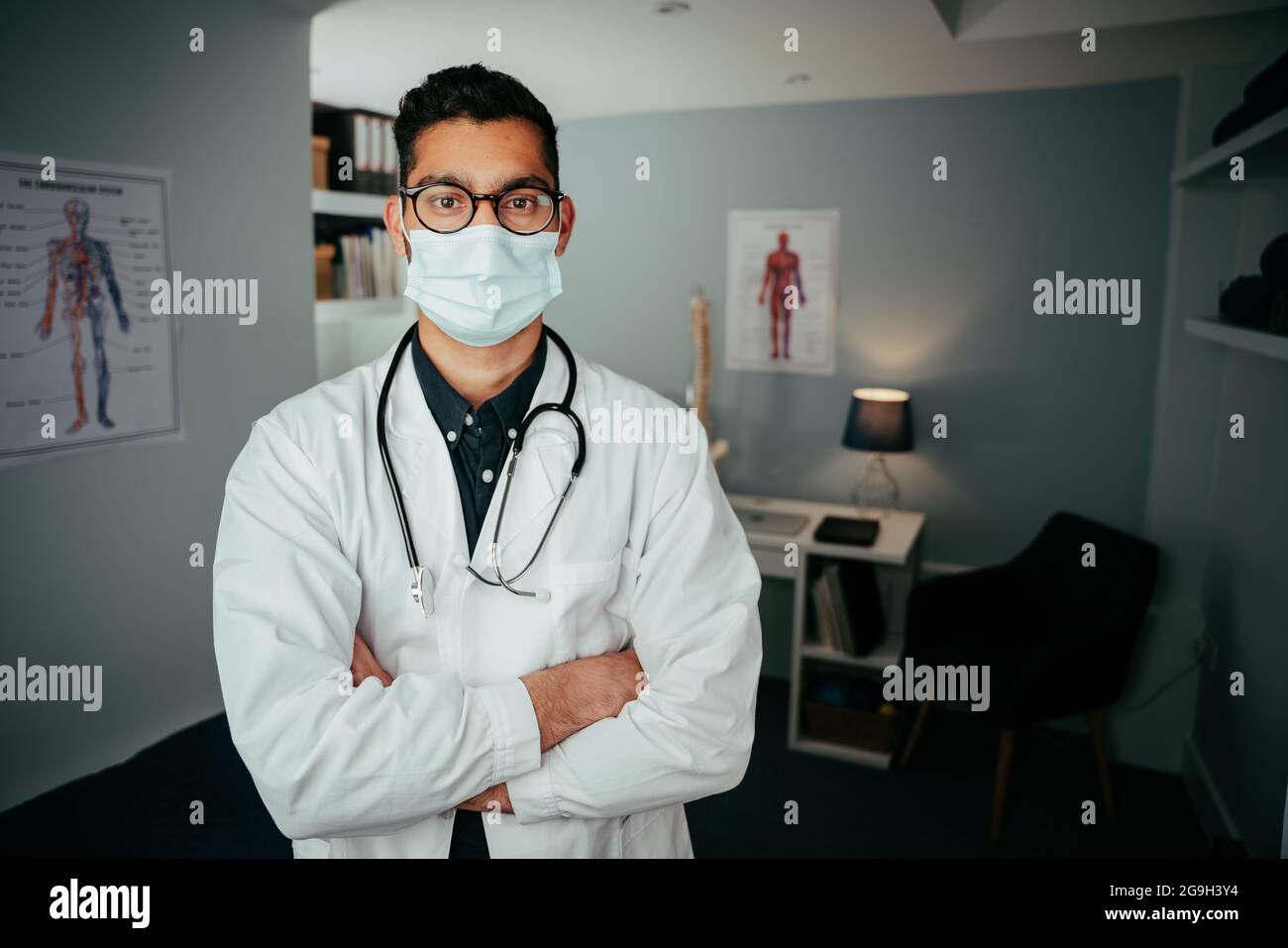 Mixed race male working in clinic wearing surgical mask Stock Photo