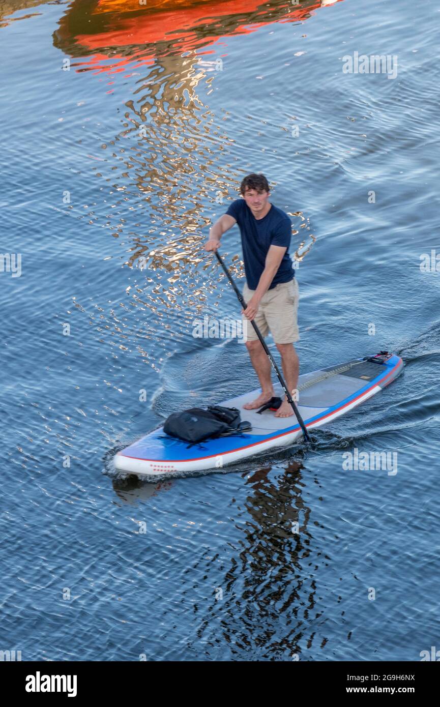 a man on a stand-up paddle board on the sea paddling wearing shorts and keeping balance. Stock Photo