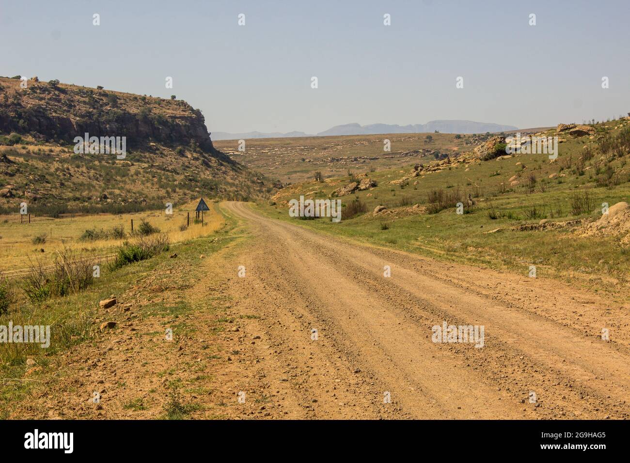 Dirt road travelling into the remote, rocky environment of the Free State Drakensberg Mountains of South Africa Stock Photo