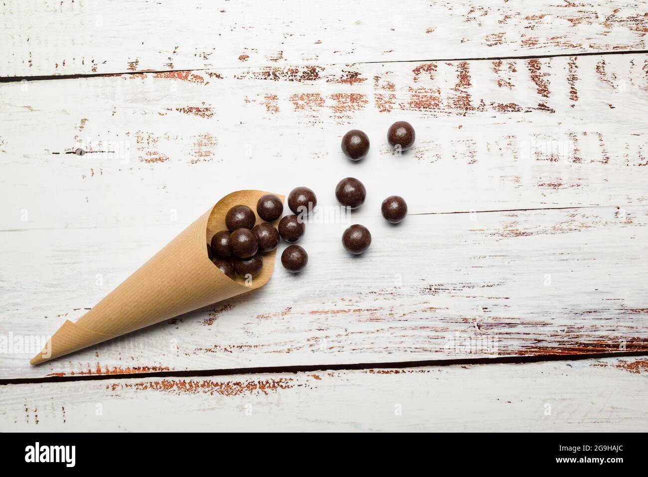 Chocolate pralines in paper cone on wooden table. Stock Photo