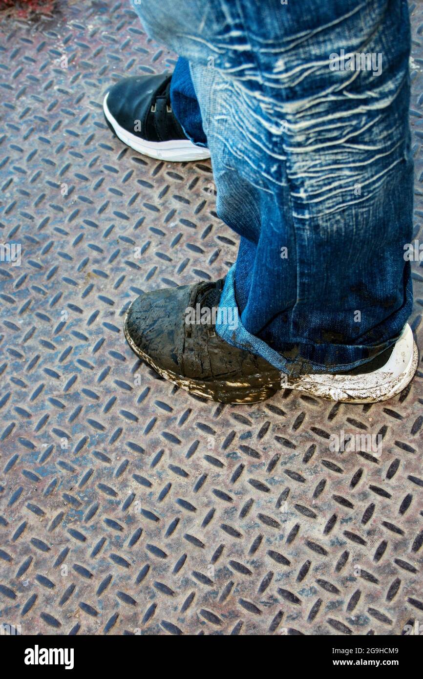 Photo of a dirty pair of tennis shoes and the bottom of a blue jean Stock Photo