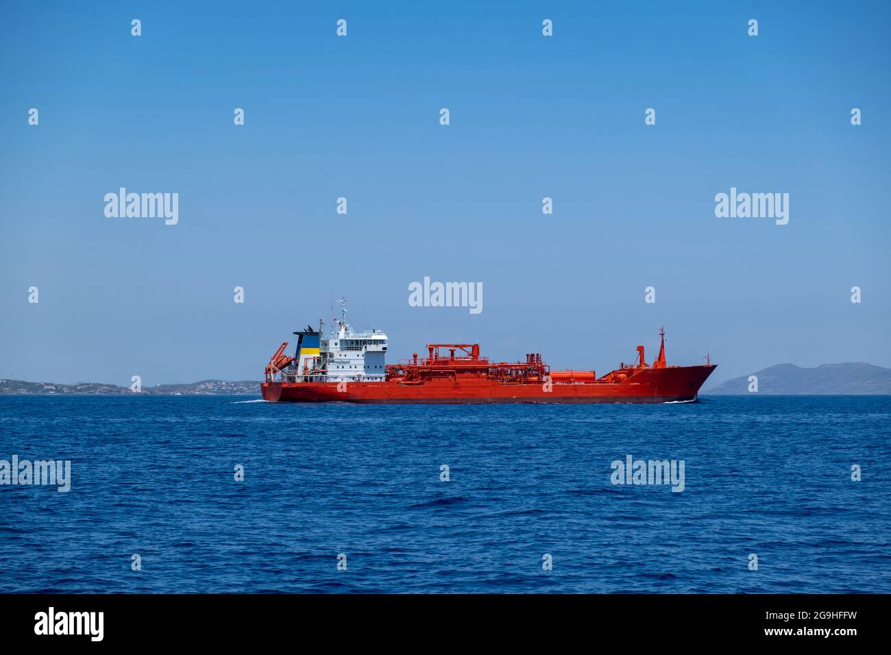 Chemical oil tanker ship, red color vessel carrying in bulk chemicl liquids, Greek Cyclades islands supplies, blue Aegean sea and clear sky background Stock Photo