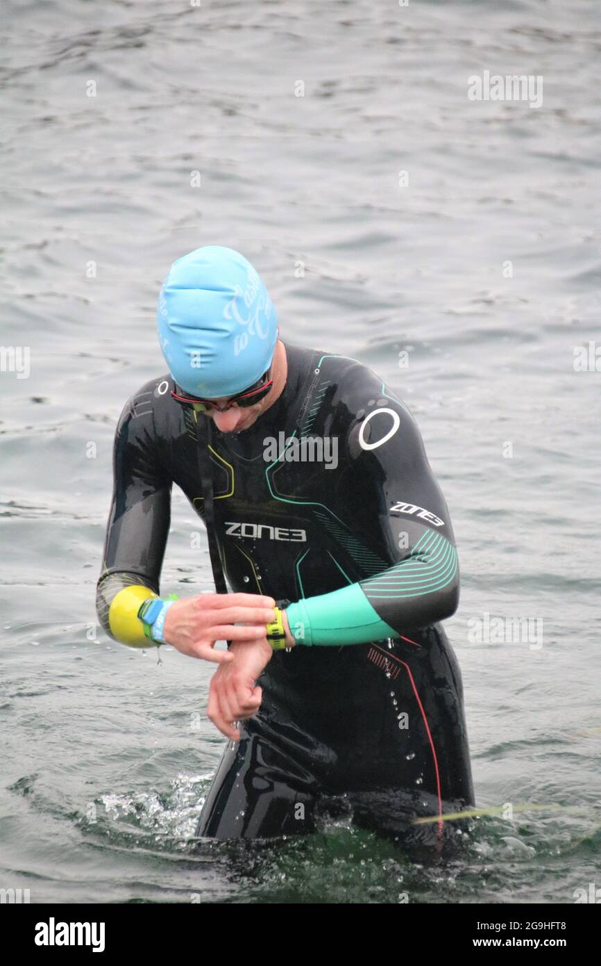swimming checking time on sport watch as he leaves a lake in a triathlon Stock Photo