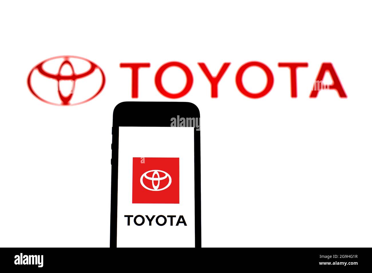 In this photo illustration a Toyota Motor Corporation logo seen displayed on a smartphone with a Toyota Motor Corporation logo in the background. Stock Photo