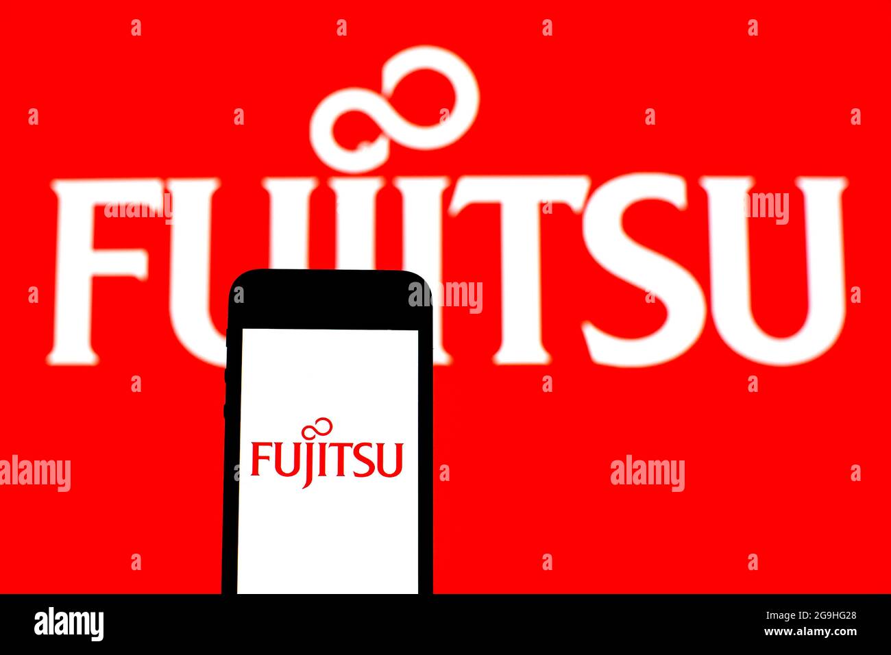 In this photo illustration a Fujitsu Limited logo seen displayed on a smartphone with a Fujitsu Limited logo in the background. Stock Photo