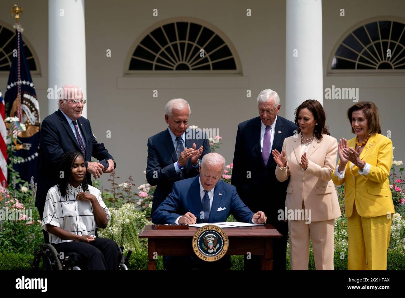 Tyree Brown, from left, Senator Patrick Leahy, a Democrat from Vermont, former Representative Tony Coelho, House Majority Leader Steny Hoyer, a Democrat from Maryland, U.S. Vice President Kamala Harris, and Speaker of the House Nancy Pelosi, a Democrat from California, applaud as U.S. President Joe Biden, center, signs a proclamation during an event marking the 31st anniversary of the Americans with Disabilities Act (ADA) in the Rose Garden of the White House in Washington, D.C., U.S., on Monday, July 26, 2021. The Biden administration is keeping foreign travel restrictions in place amid conce Stock Photo