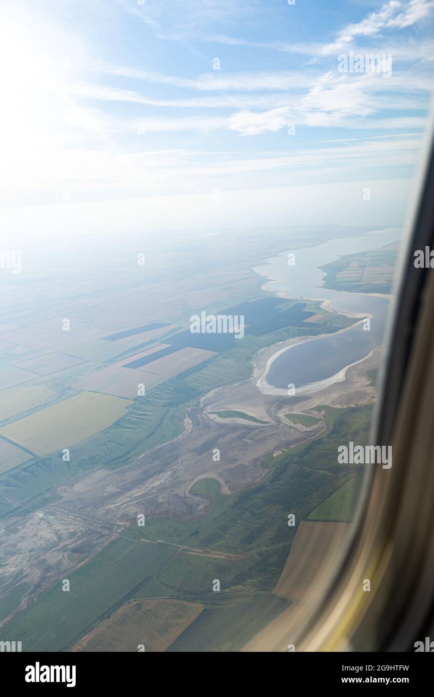 Land view through the airplane window. Fields, roads, rivers from a