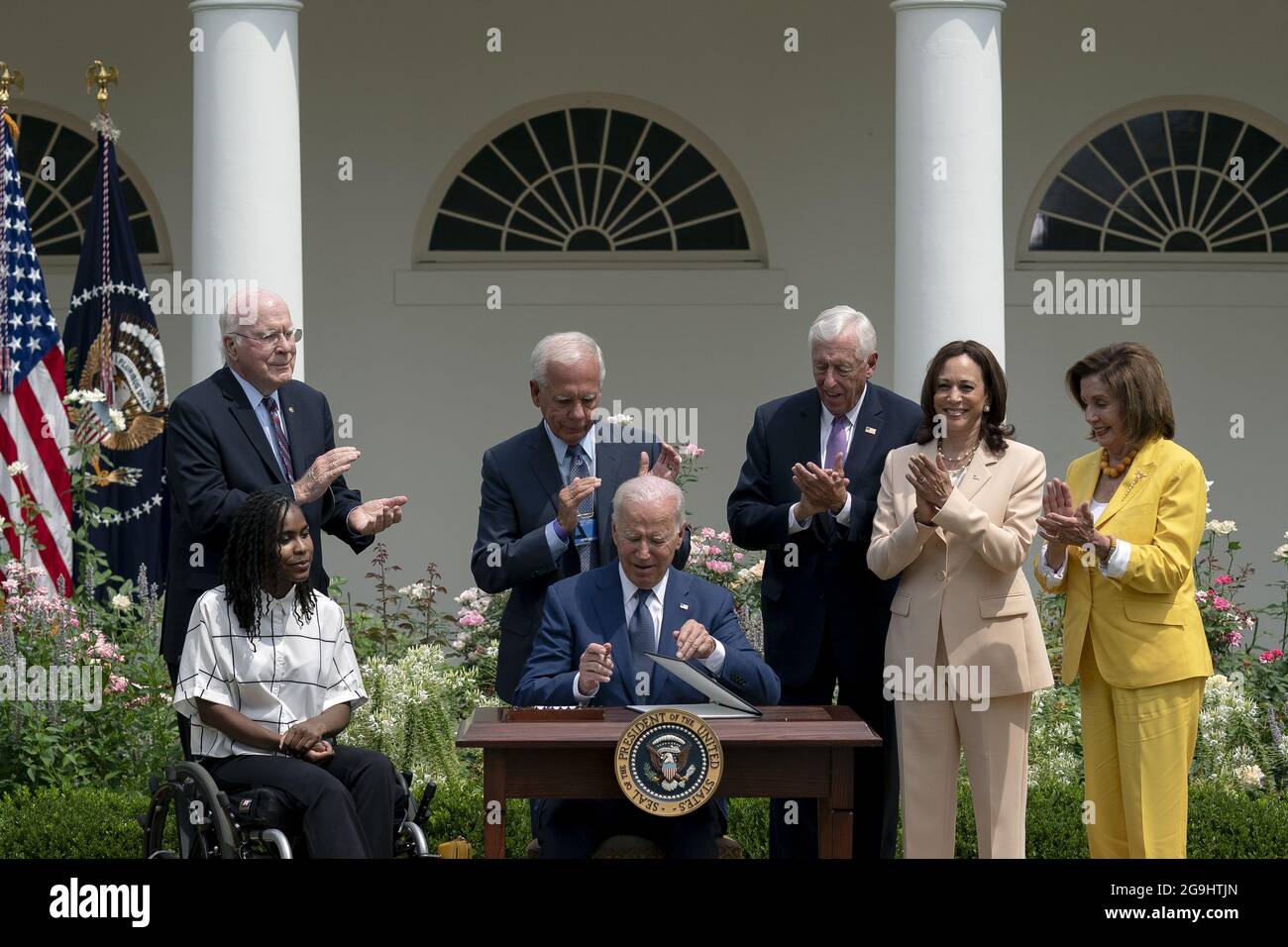 Tyree Brown, from left, Senator Patrick Leahy, a Democrat from Vermont, former Representative Tony Coelho, House Majority Leader Steny Hoyer, a Democrat from Maryland, U.S. Vice President Kamala Harris, and Speaker of the House Nancy Pelosi, a Democrat from California, applaud as U.S. President Joe Biden, center, signs a proclamation during an event marking the 31st anniversary of the Americans with Disabilities Act (ADA) in the Rose Garden of the White House in Washington, DC, U.S., on Monday, July 26, 2021. The Biden administration is keeping foreign travel restrictions in place amid conce Stock Photo