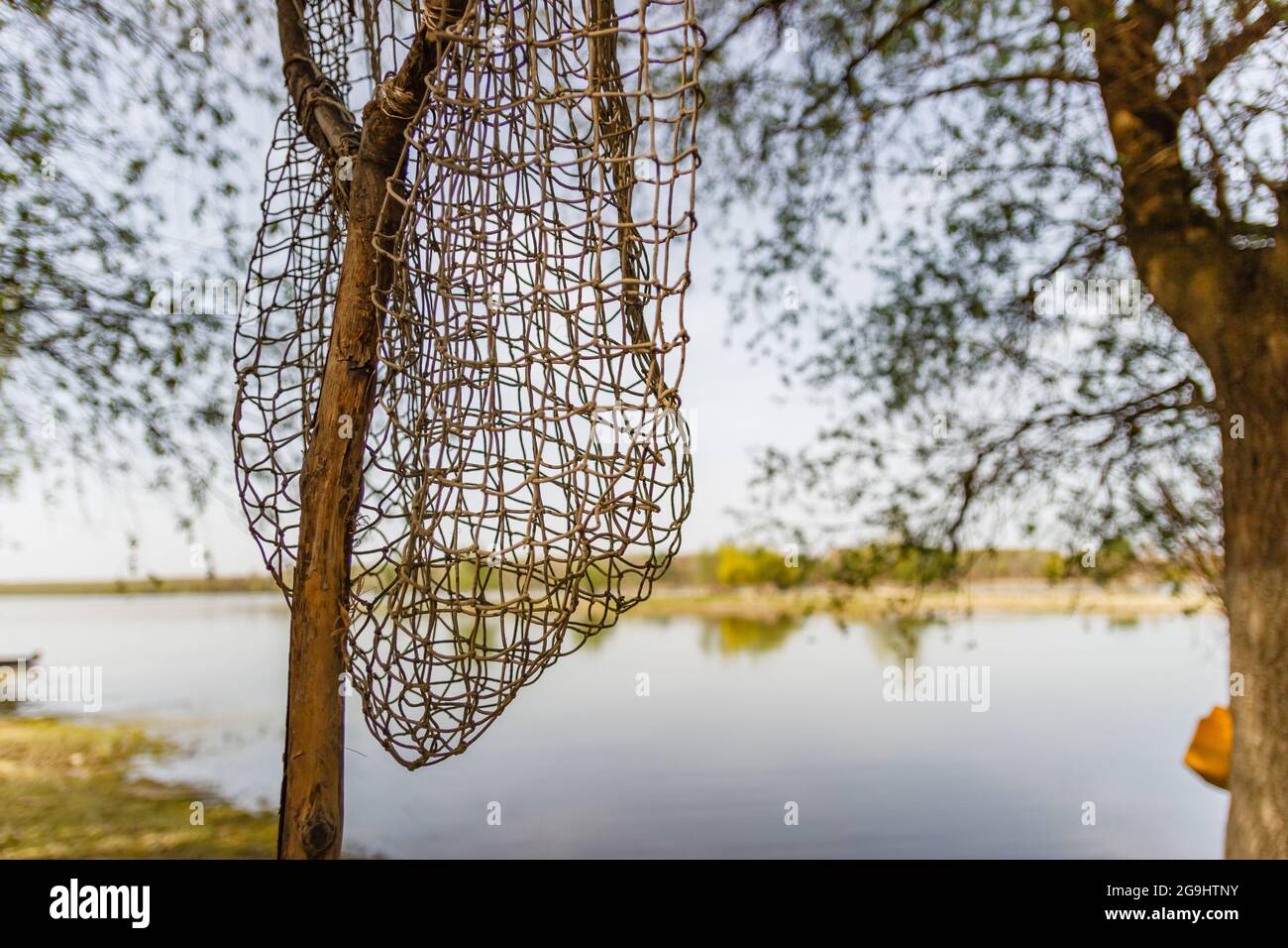 Fish net hanging on the tree next to a lake Stock Photo - Alamy