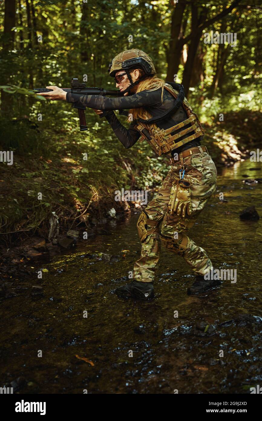 Woman in uniform using dangerous weapon outdoors Stock Photo