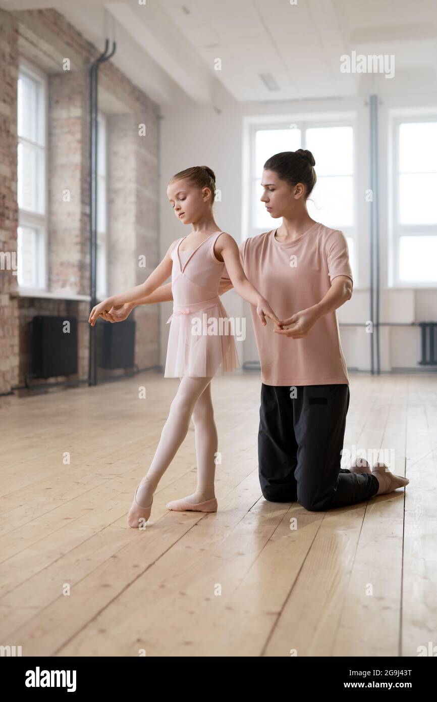 Young trainer showing to her student the right position in ballet during their classes in dance studio Stock Photo