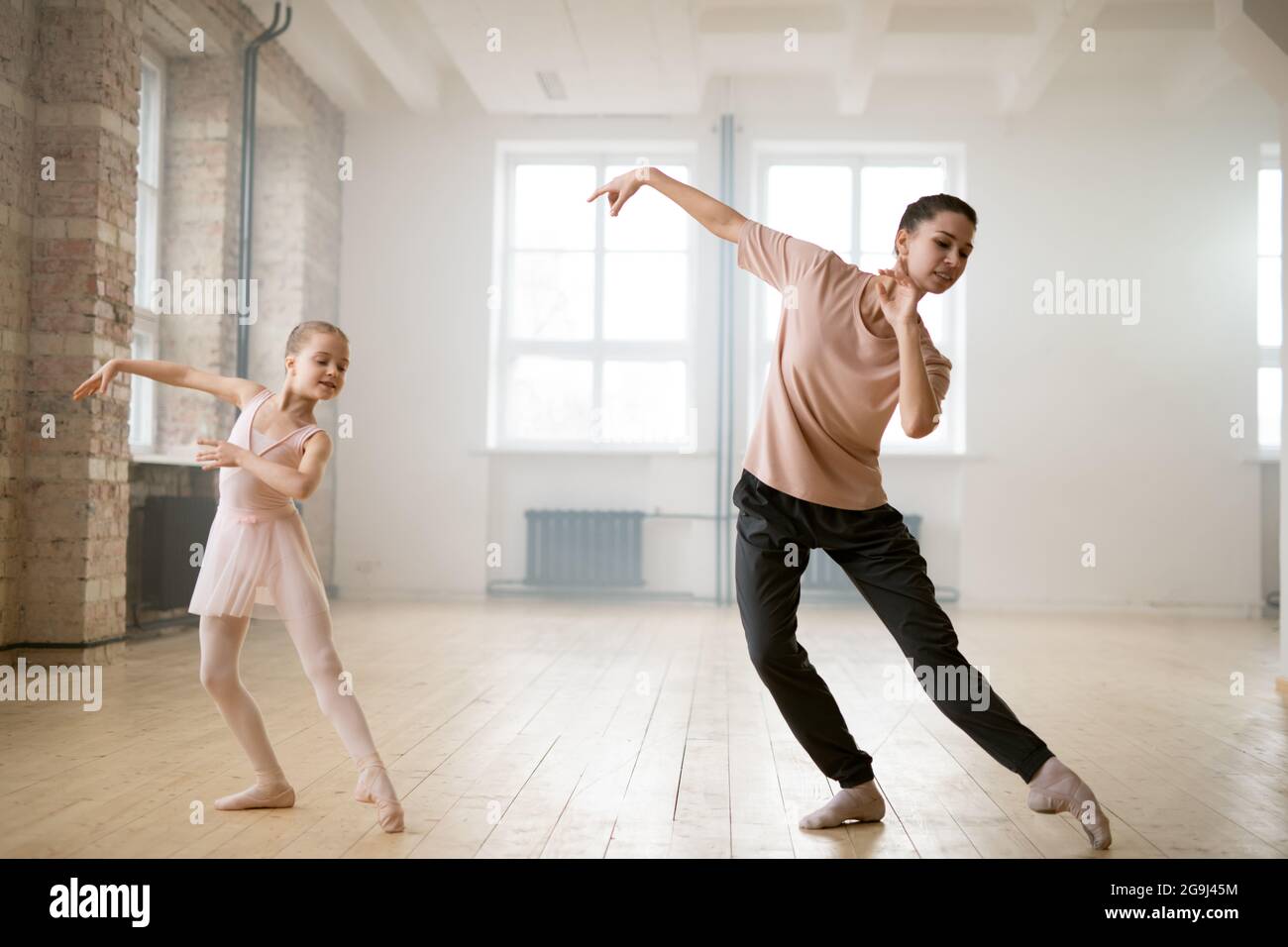 Young woman watching for the movements of her student while she dancing during classes in dance studio Stock Photo