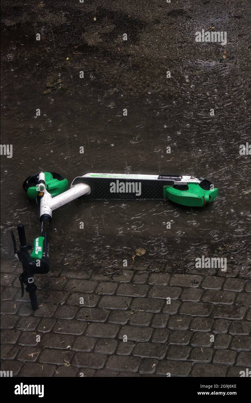 An electric scooter abandoned fallen and stuck in a heavy rain flood