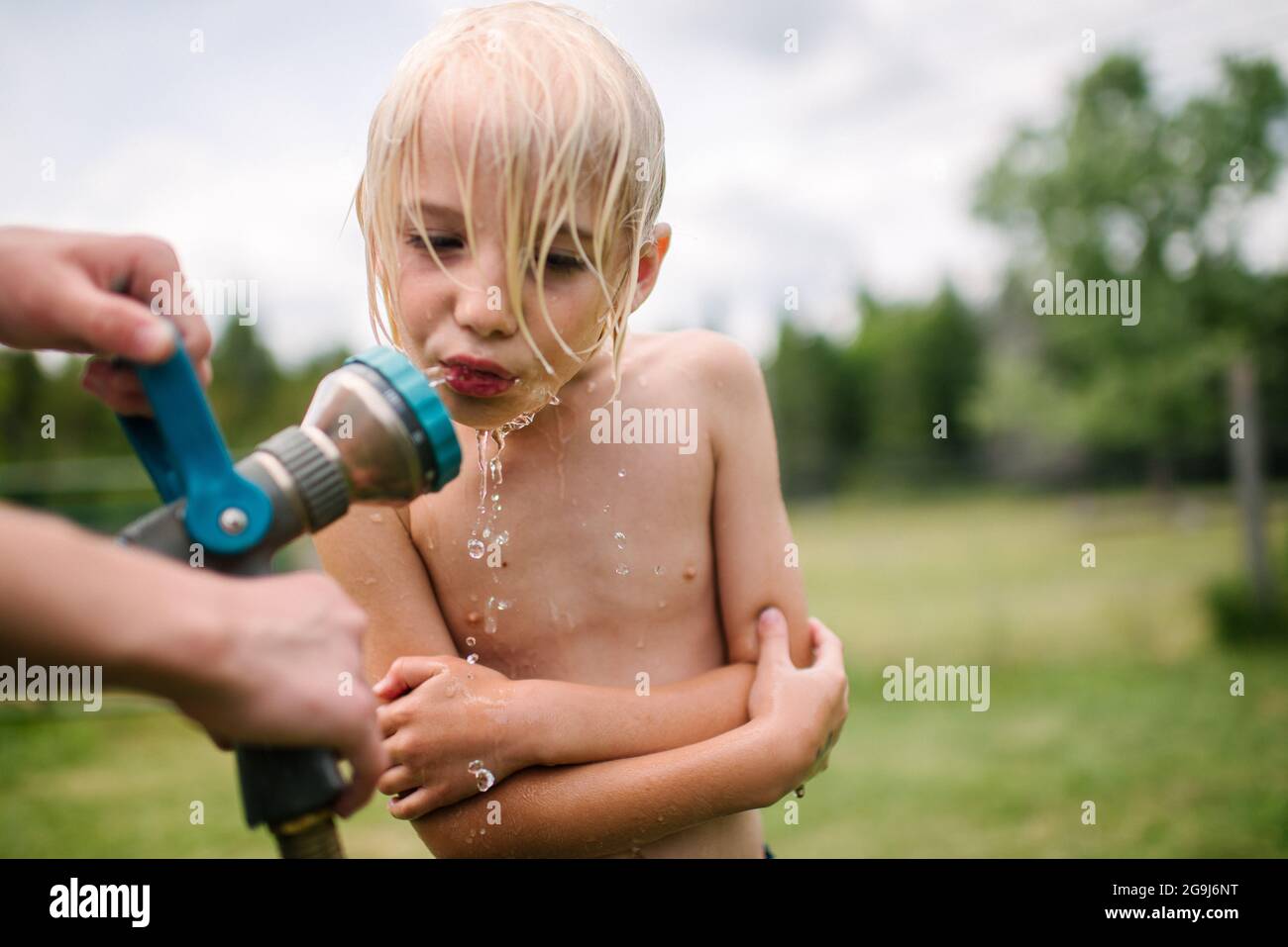 Canada, Ontario, Kingston, Boy (8-9) drinking from water hose Stock Photo