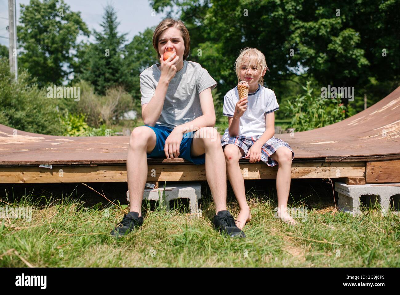 Canada, Ontario, Kingston, Boys (8-9, 14-15) eating ice cream and apple Stock Photo