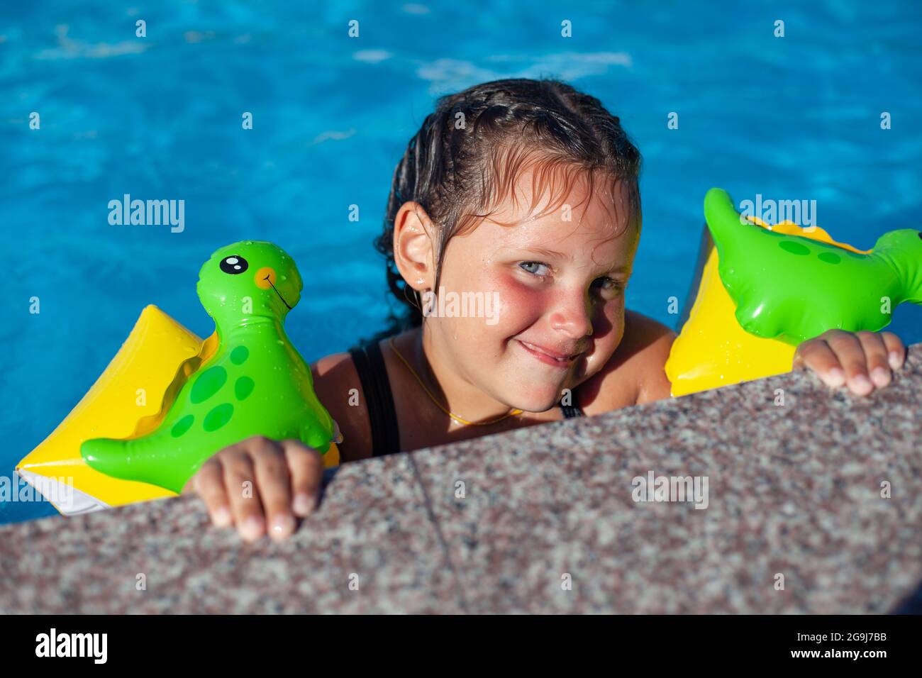 A child in inflatable armbands. A cheerful sixyearold girl in