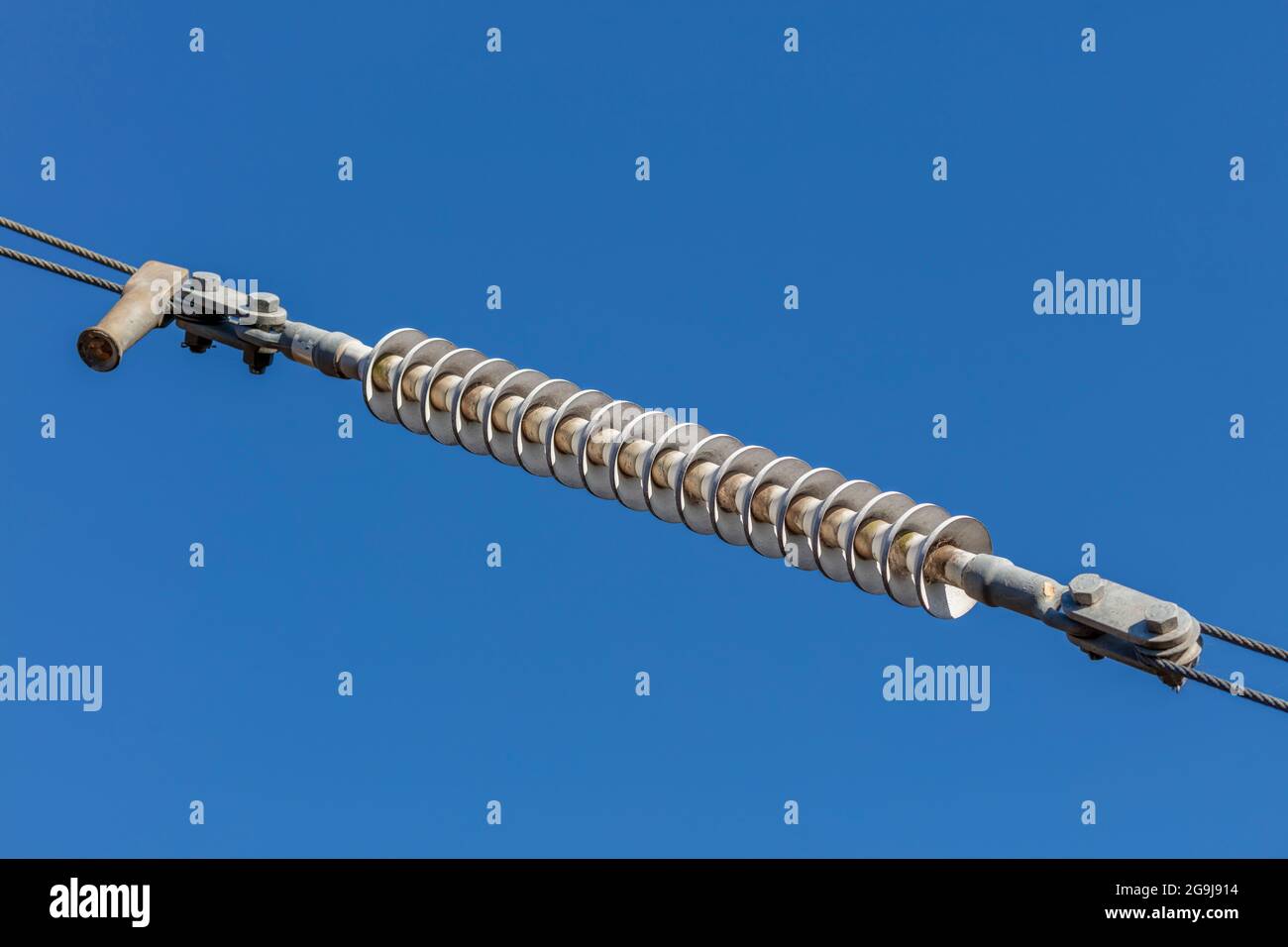 Photograph of a tensioner bracket on a transmission line against a bright blue sky Stock Photo