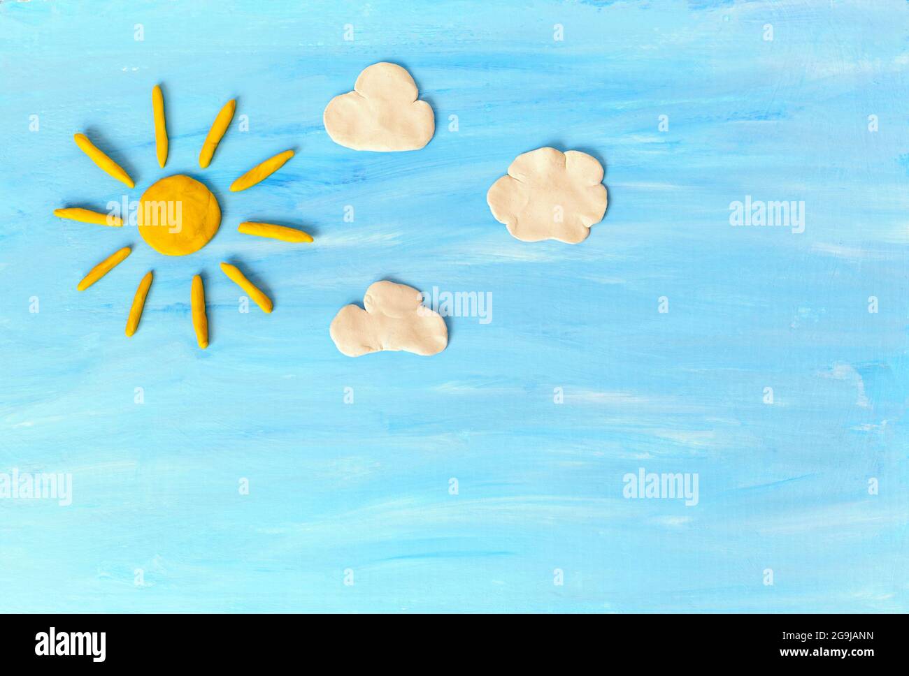 Sun, clouds on blue sky. Made from plasticine Stock Photo
