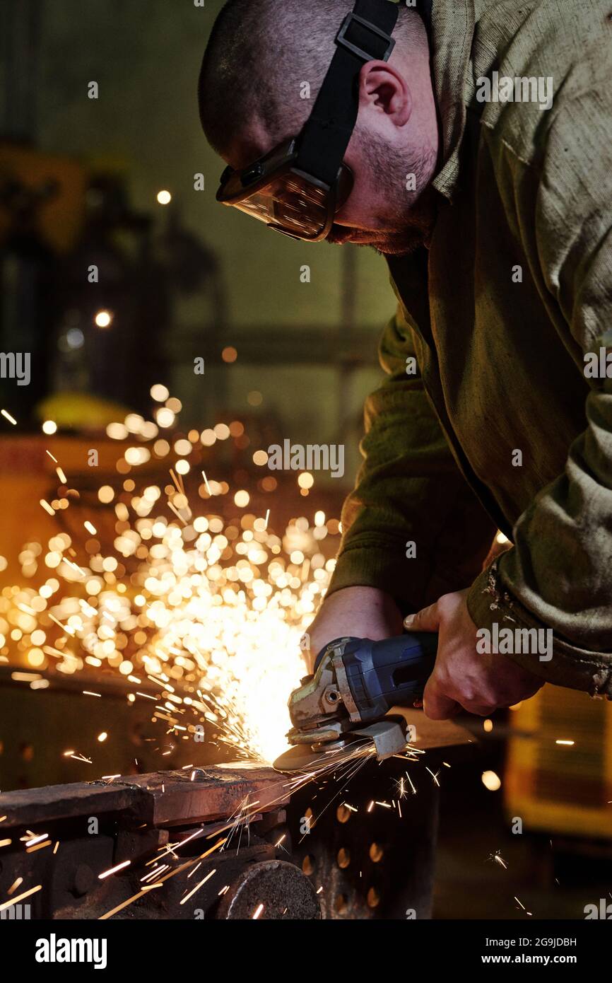 Workers wearing industrial uniforms and welded iron mask at steel welding plants Stock Photo