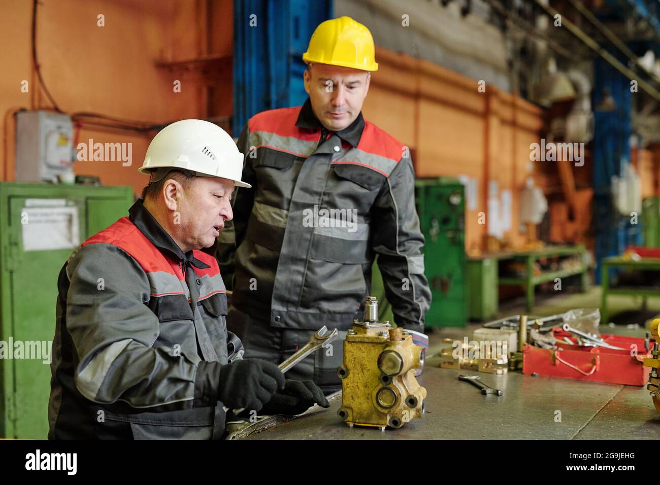 Mature engineer in workwear working with metal equipment in the machinery factory Stock Photo
