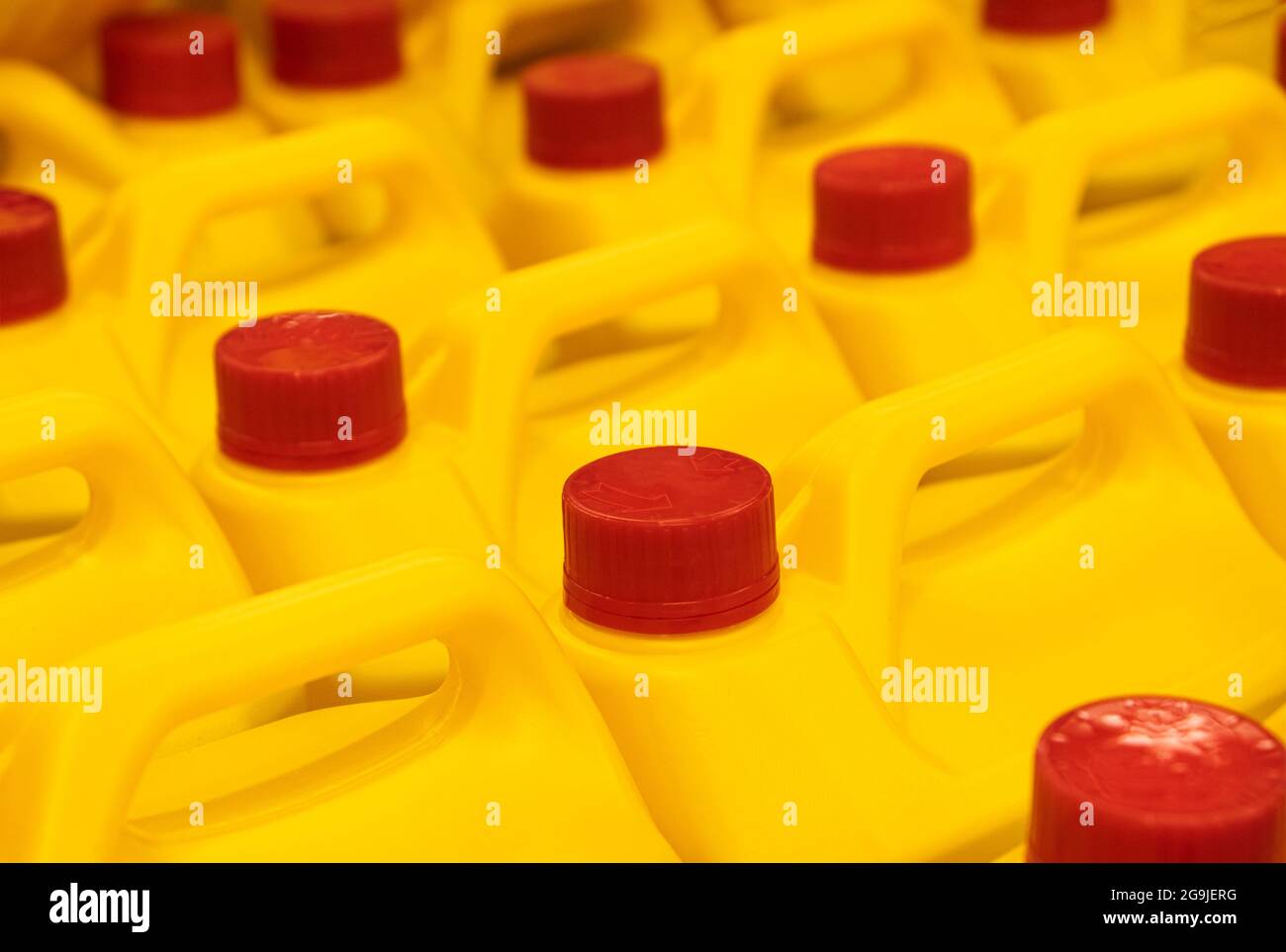 Yellow Plastic bottles cans Yellow household chemicals Liquid Refill in the hardware warehouse store. Stack of Canisters with red plastic cork cap. Stock Photo