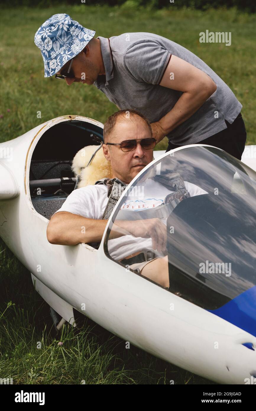 Glider pilot getting ready for flight on fixed-wing aircraft from parking airfield. Man sitting in cabin before taking off. Soaring sport club Stock Photo