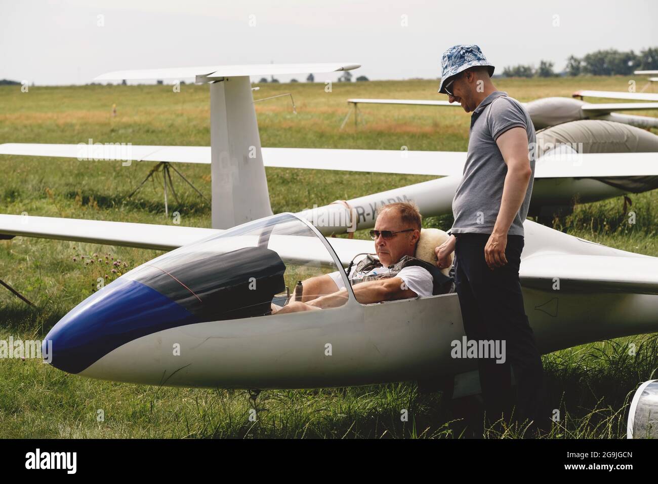 Soaring club, getting ready for the flight on glider airplane. Small aviation sport. Two man checking cabin instrument panel of vintage airplane Stock Photo