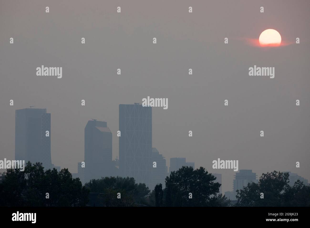Sun setting through haze over Calgary caused by wildfire smoke from BC during the heatwave. A warning with Air Quality Health Index of 6.6 was issued. Stock Photo